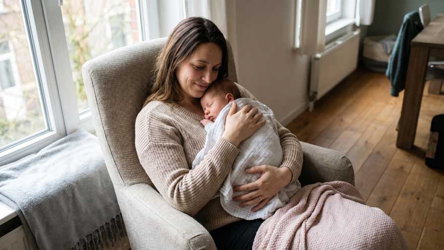 Maman berçant son bébé dans ses bras pendant une sieste de contact