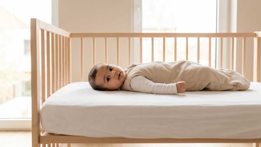 Bébé de quatre mois allongé sur le dos dans son lit observant son entourage